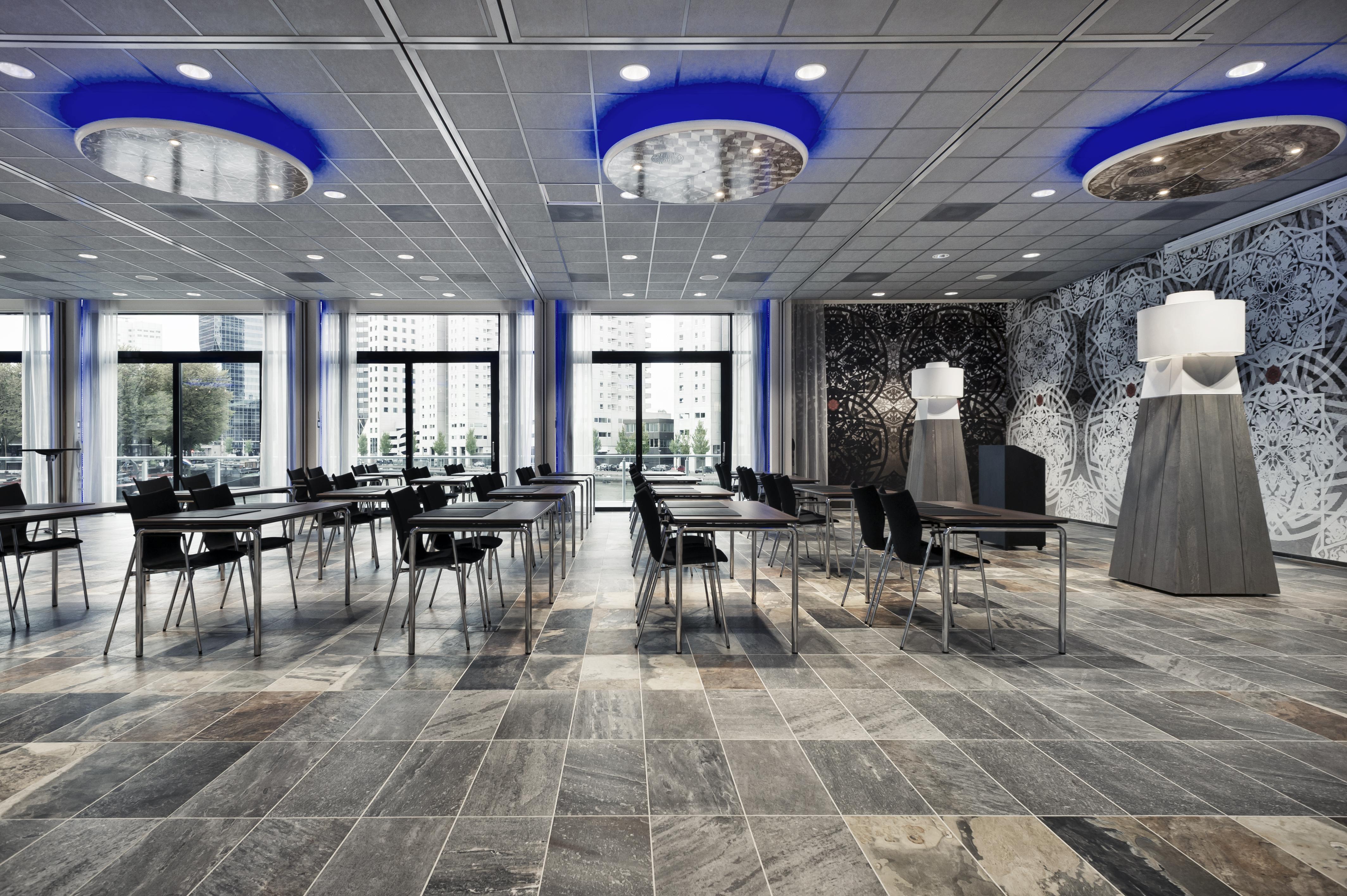 Mainport Hotel Rotterdam, A Hilton Affiliate Hotel Экстерьер фото The photo displays a modern conference or meeting room. It features a sleek design with several black chairs arranged around rectangular tables. The floor is made of elegant stone tiles, adding to the contemporary feel of the space. 

The ceiling is 