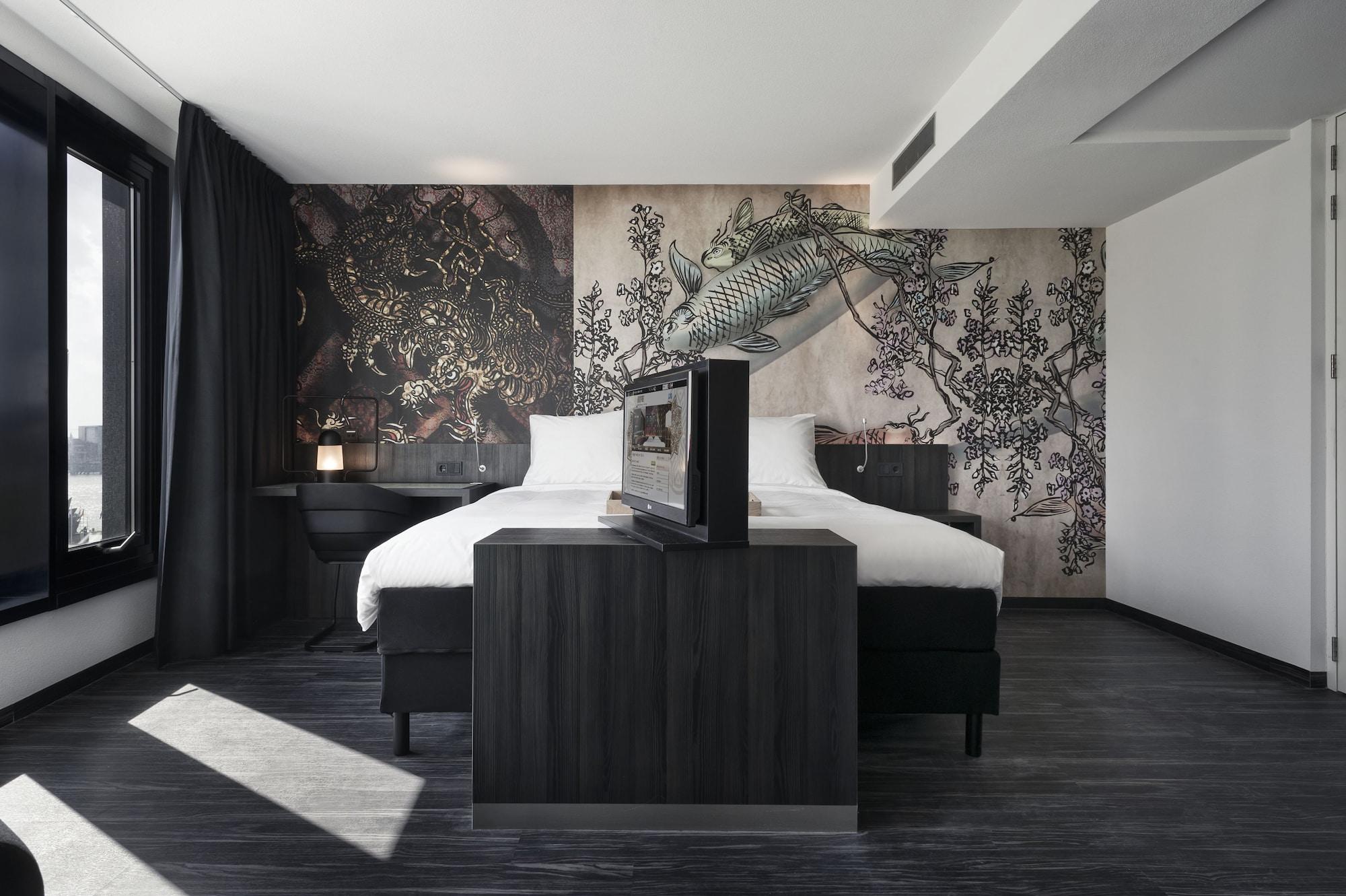 Mainport Hotel Rotterdam, A Hilton Affiliate Hotel Экстерьер фото The photo showcases a modern hotel room featuring a large bed with white linens and dark contrasting furniture. The wall behind the bed has an artistic mural of a fish and botanical elements, adding an interesting visual touch to the room. The space 