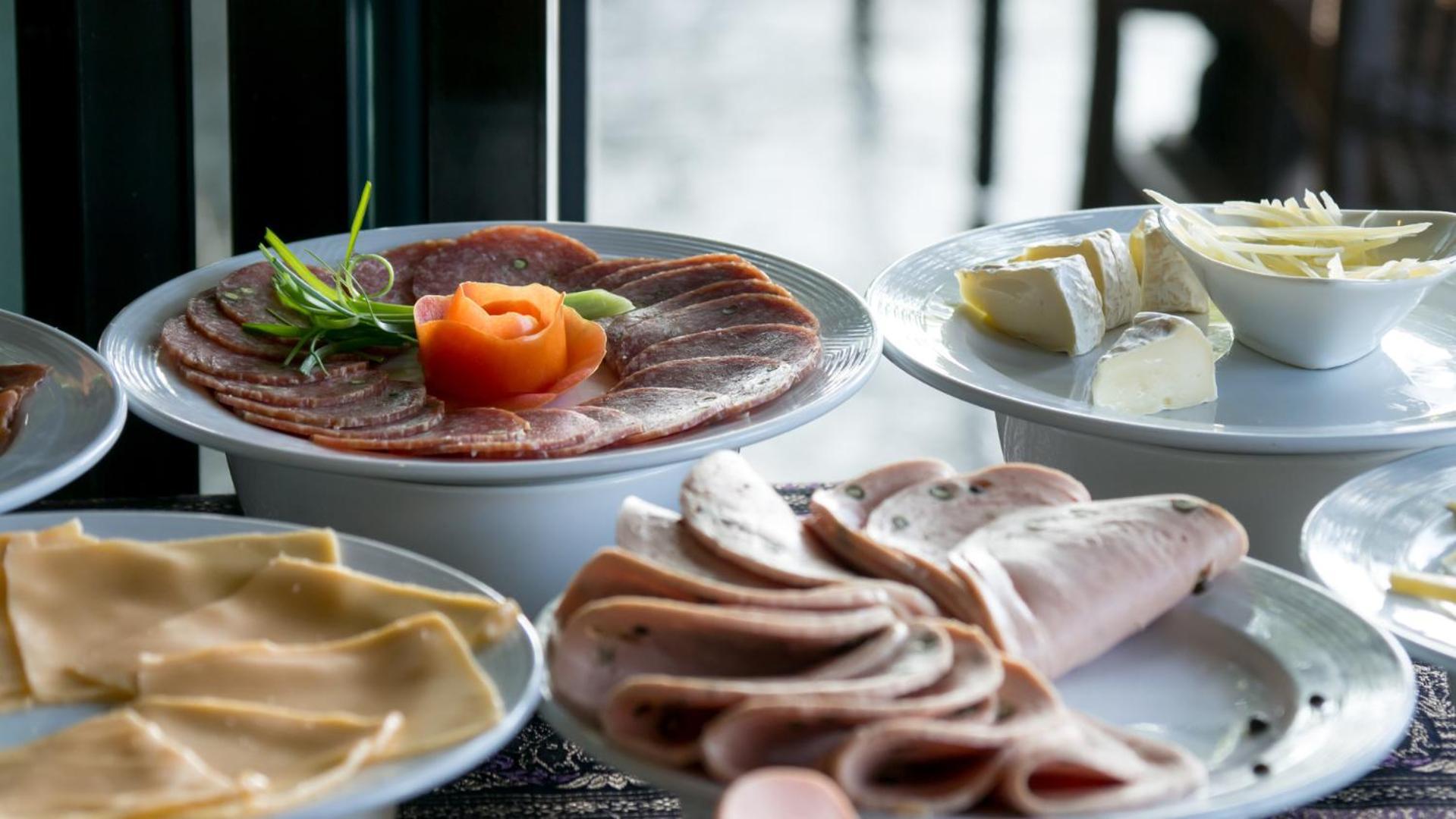 Mainport Hotel Rotterdam, A Hilton Affiliate Hotel Экстерьер фото The photo displays a selection of cured meats and cheeses arranged on plates. 

- In the foreground, there are various types of sliced meats, including what appears to be ham and possibly other cold cuts, elegantly arranged.
- In the center, a circul